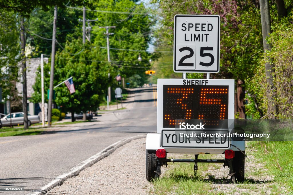 Speeding A sheriff’s radar device measures the speed of cars passing by. Speed Limit Sign Stock Photo