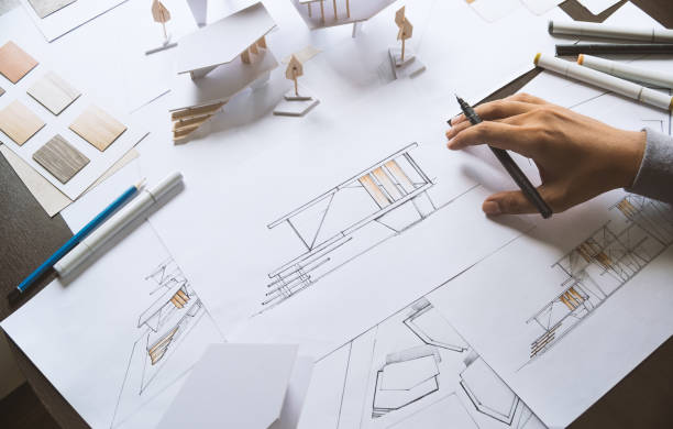 istock architect design working drawing sketch plans blueprints and making architectural construction model in architect studio 1169370148