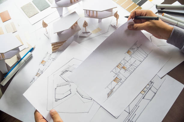 istock architect design working drawing sketch plans blueprints and making architectural construction model in architect studio 1169370150