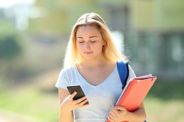 istock Serious student walks checking text on phone 1169370467