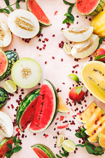 Summer fruit and vegetable variety.  .Assorted types of slices watermelon, melon, pomegranate and peaches on rustic surface.  Top view, blank space