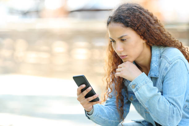 istock Mixed race woman using smart phone in a park 1169370645