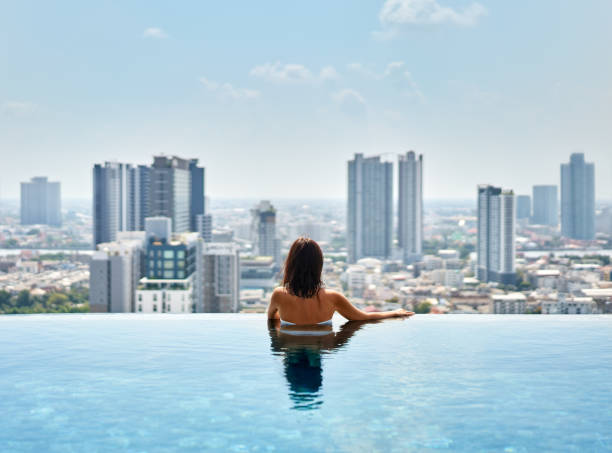 молодая женщина отдыхает на краю бассейна на крыше - poolside enjoyment sensuality blue стоковые фото и изображения