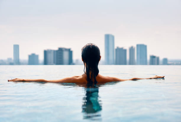 bavk вид молодой женщины плавание в бассейне на крыше - poolside enjoyment sensuality blue стоковые фото и изображения