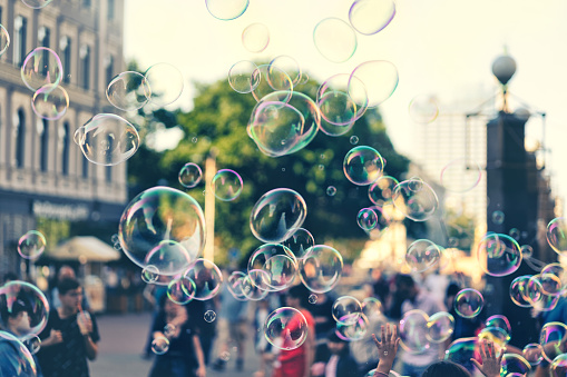 People play with soap bubbles on a square in Riga on a summer sunny day.