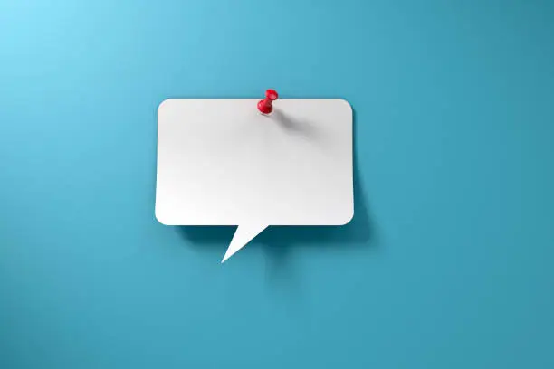 White chat bubble with red thumbtack on vibrant blue background with copy space.