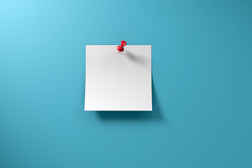 Blank adhesive sticky note and red thumbtack on a blue background with copy space.