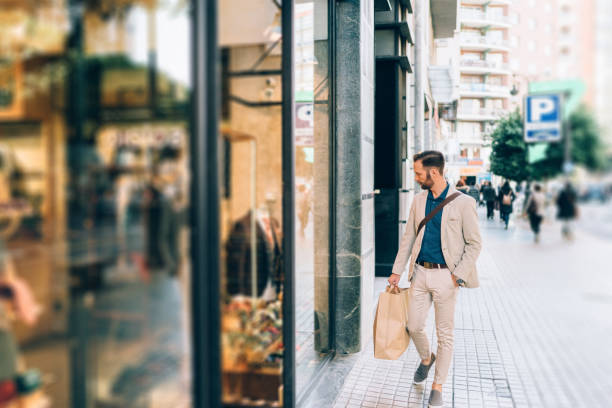 Businessman shopping in Valencia Businessman with shopping bag looking at shop window in the city window shopping stock pictures, royalty-free photos & images
