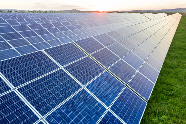 blue solar photo voltaic panels system producing renewable clean energy on rural landscape and setting sun background. - voltaic imagens e fotografias de stock
