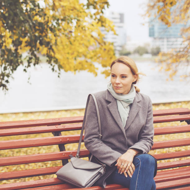istock Young woman in grey coat sitting on a bench 1169377291