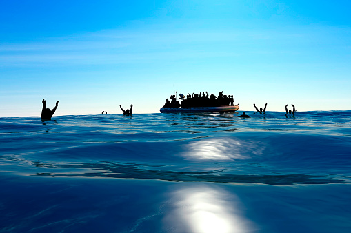 Refugees on a big rubber boat in the middle of the sea that require help.
