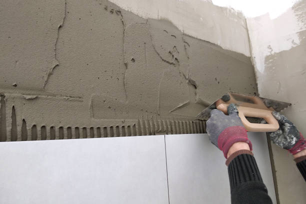 istock Worker hands putting ceramic tiles on the wall. 1169379575