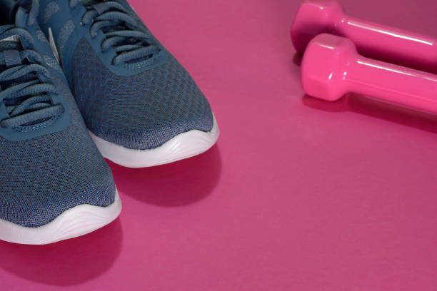 istock Sport sneakers and dumbbells on pink background with copy space for text. Sport objects background. Sports concept 1169387935