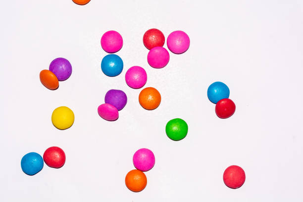Rainbow colored chocolate coated candies on white isolated background