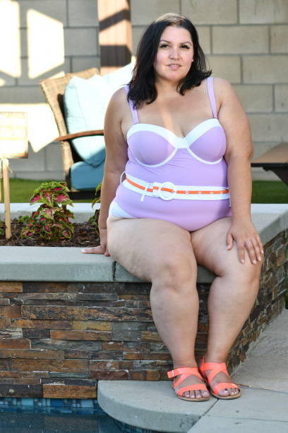 Young Woman in Purple Swimsuit sitting on planter smiling Melissa Hernandez modeling in a Backyard Pool steven harrie stock pictures, royalty-free photos & images