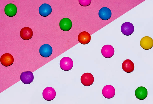 istock Chocolate coated candies on pink and white background 1169389556