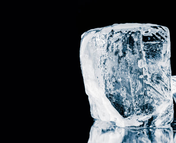 istock Textured translucent ice block on black reflective background. 1169389839