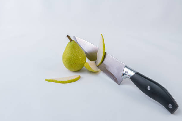 istock A knife with pear slices accompanied by a whole green pear on a white background - Freshly harvested pears 1169399620