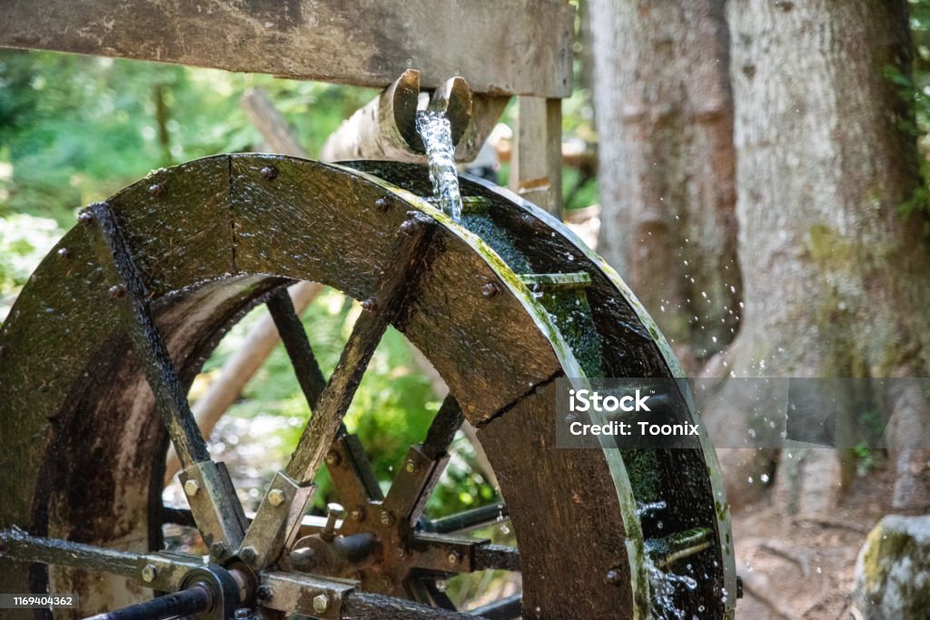 A waterwheel in the forest with motion blur added. A water wheel in a forest Watermill Stock Photo