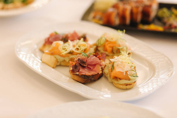 istock Appetizer in restaurant. Banquet concept. Bruschette with salmin and ham, decorated with basil and chile 1169404385