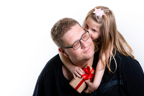 Father's Day. Happy family daughter hug father and kiss his face with gift in hands. White background, copy space.