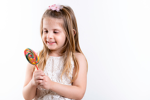 Cute Girl, girl with colored candy lollipop. Children's Day. White background, copy space.