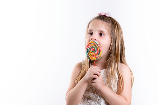 Cute Girl, girl with colored candy lollipop. Children's Day. White background, copy space.