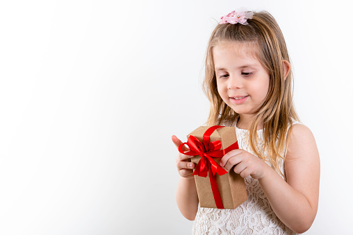 Cute Girl, Girl holding gift with red bow on Children's Day. White Background, copy space.