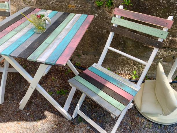 istock Multi colored shabby chic table and chair at the wall 1169417454