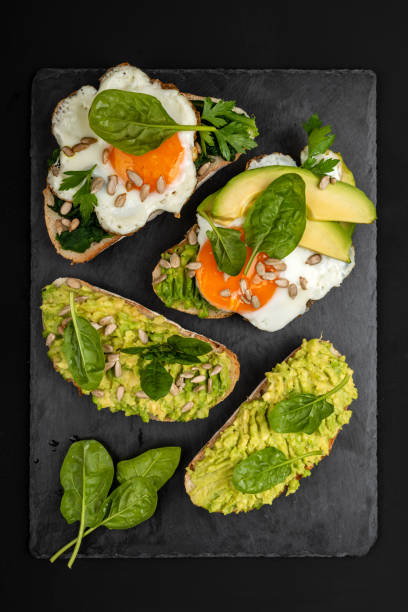 istock Sandwiches with avocado, spinach and fried eggs on a black background 1169420255