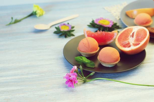 Natural ice cream, sorbet, grapefruit, mint, flowers on a wooden table