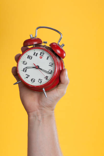 istock Hand holding a red watch on a yellow background 1169426769