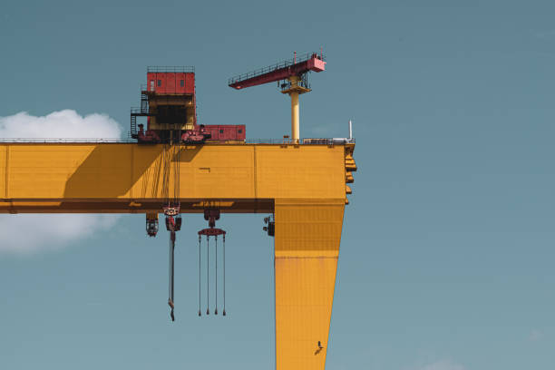 Yellow gantry crane towering over dry dock of a shipyard