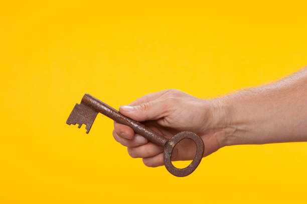 istock Hand holding a corroded key on a yellow background 1169428728