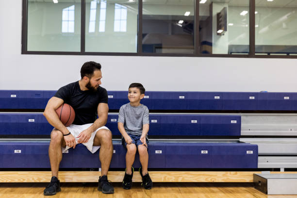 l'oncle adulte et le jeune neveu s'asseyaient sur des gradins et parlent - sport parent bleachers family photos et images de collection