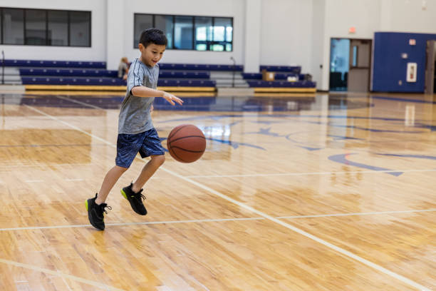 ragazzo pratica dribbling basket in palestra scuola - dribbling foto e immagini stock