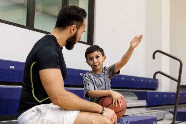 sentado en las gradas, hijo pequeño describe el juego a papá atento - sport parent bleachers family fotografías e imágenes de stock