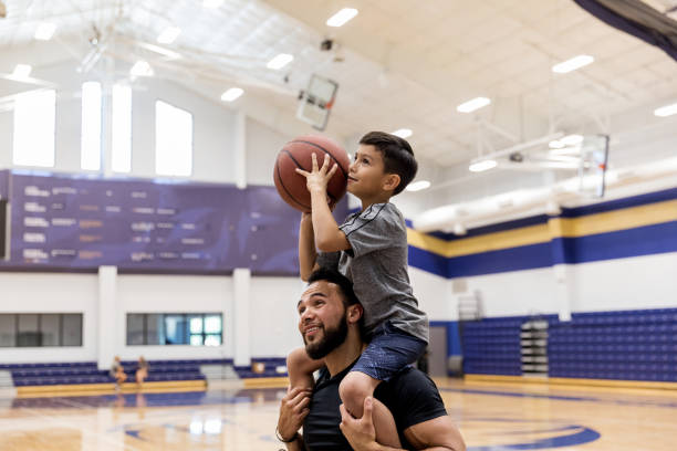 istock Father has son on shoulders to shoot baskets at gym 1169431746