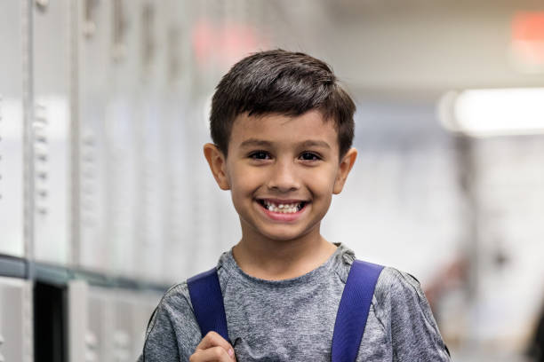 istock Cheerful, cute young boy with backpack by open locker 1169431755