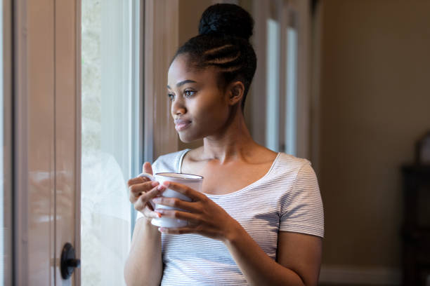 istock Woman day dreams while looking through window 1169431841