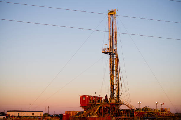 istock Oil Drilling Rig Vertical Derrick Glowing at Sunset 1169432757