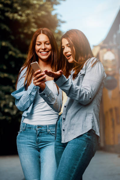 istock Two young women using smartphone in the street 1169437104