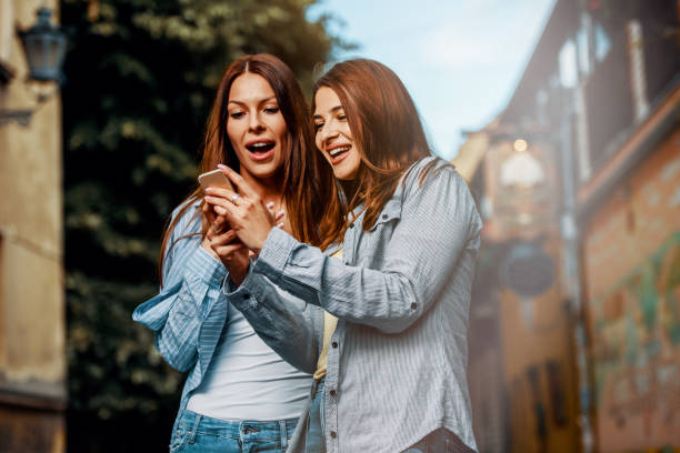 istock Two young women using smartphone in the street 1169437235