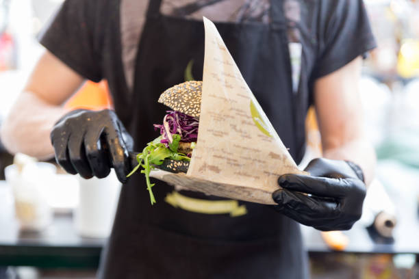 국제 도시 길거리 음식 축제에서 유기농 채식 생선 버거를 제공하는 요리사. - black gloves 뉴스 사진 이미지