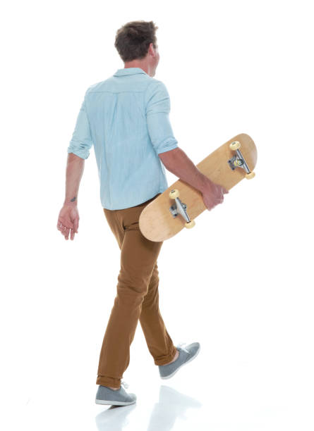 istock Casual well dressed man walking with a skateboard 1169440947