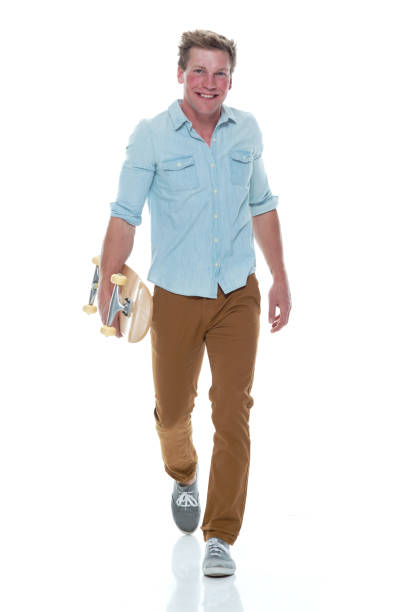 istock Casual well dressed man walking with a skateboard 1169440966