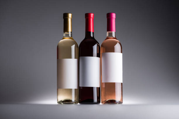 bottiglie di vino rosso, bianco e rosato con etichette bianche su sfondo scuro con retro chiaro - bottle wine white blank foto e immagini stock