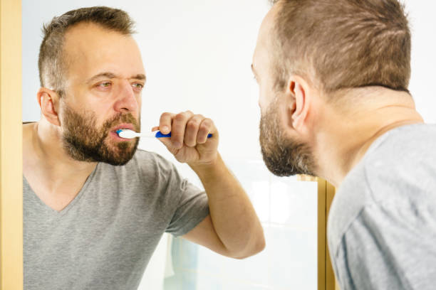 istock Man brushing his teeth in bathroom 1169443298