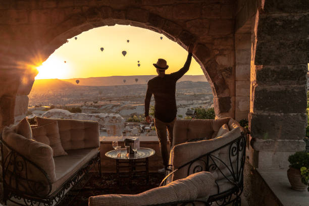 Rear View Of A Young Man Watching Ballooning Festival At Sunset Rear View Of A Young Man Watching Ballooning Festival At Sunset cappadocia photos stock pictures, royalty-free photos & images