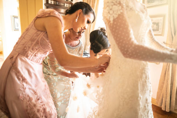 istock Bridesmaids helping bride getting dressed for the wedding ceremony 1169459786